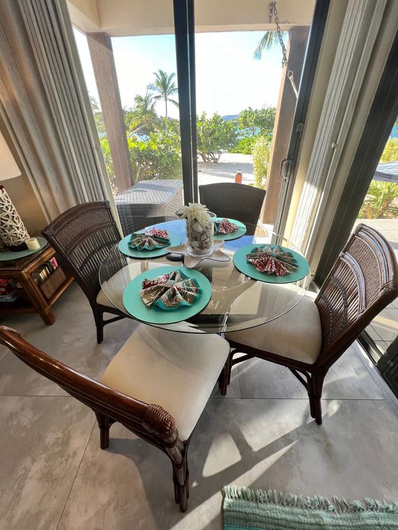 Dining table for four beside the ocean-facing glass doors of this last-minute St. Thomas beachfront condo