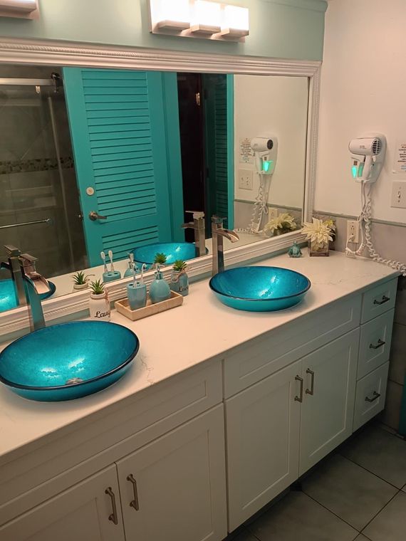Bathroom mirror, hair dryer and turquoise louvered shutters in the St. Thomas condo with a patio on the beach